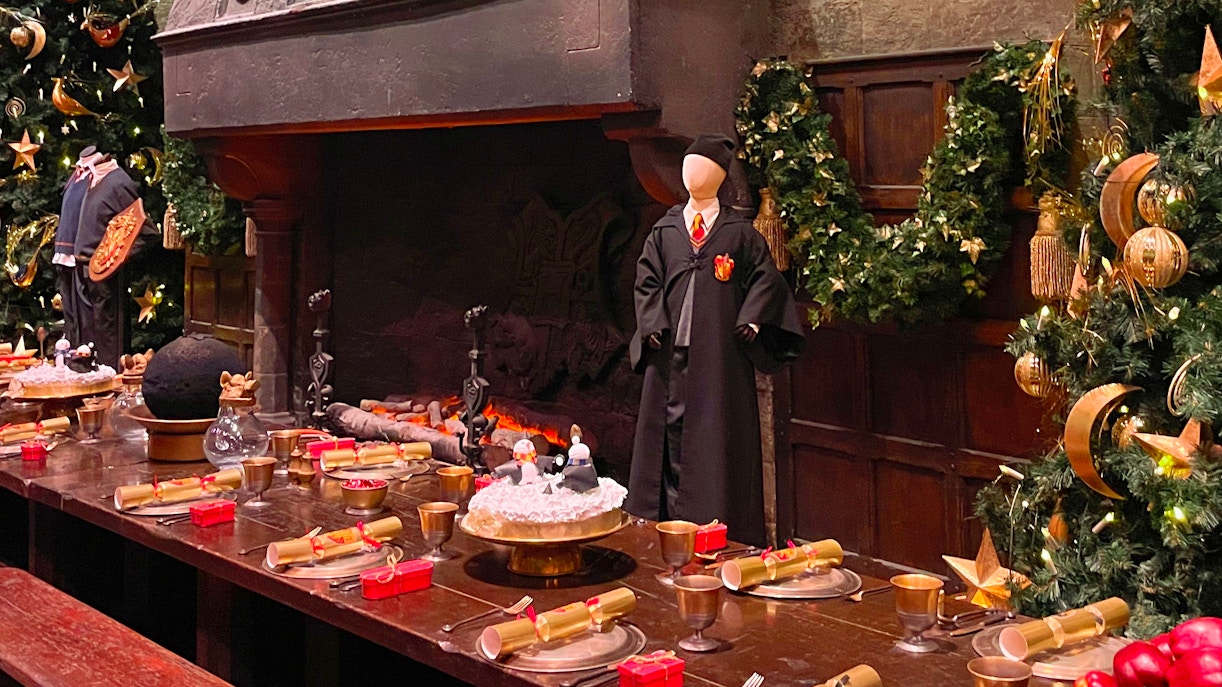 Hogwarts dining hall with festive decorations and a Gryffindor robe on display.
