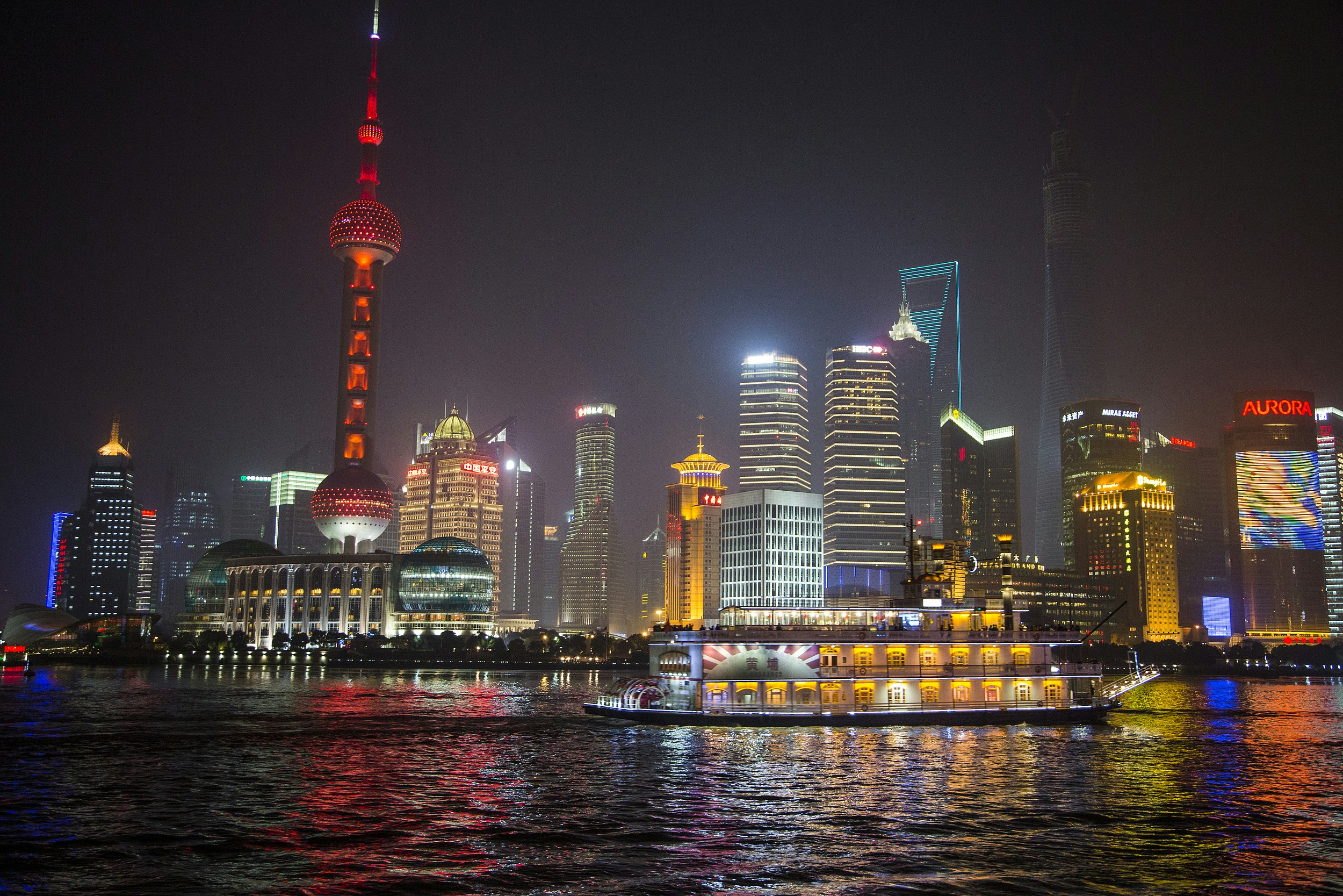 Huangpu River cruise with Shanghai skyline and Oriental Pearl Tower at night.