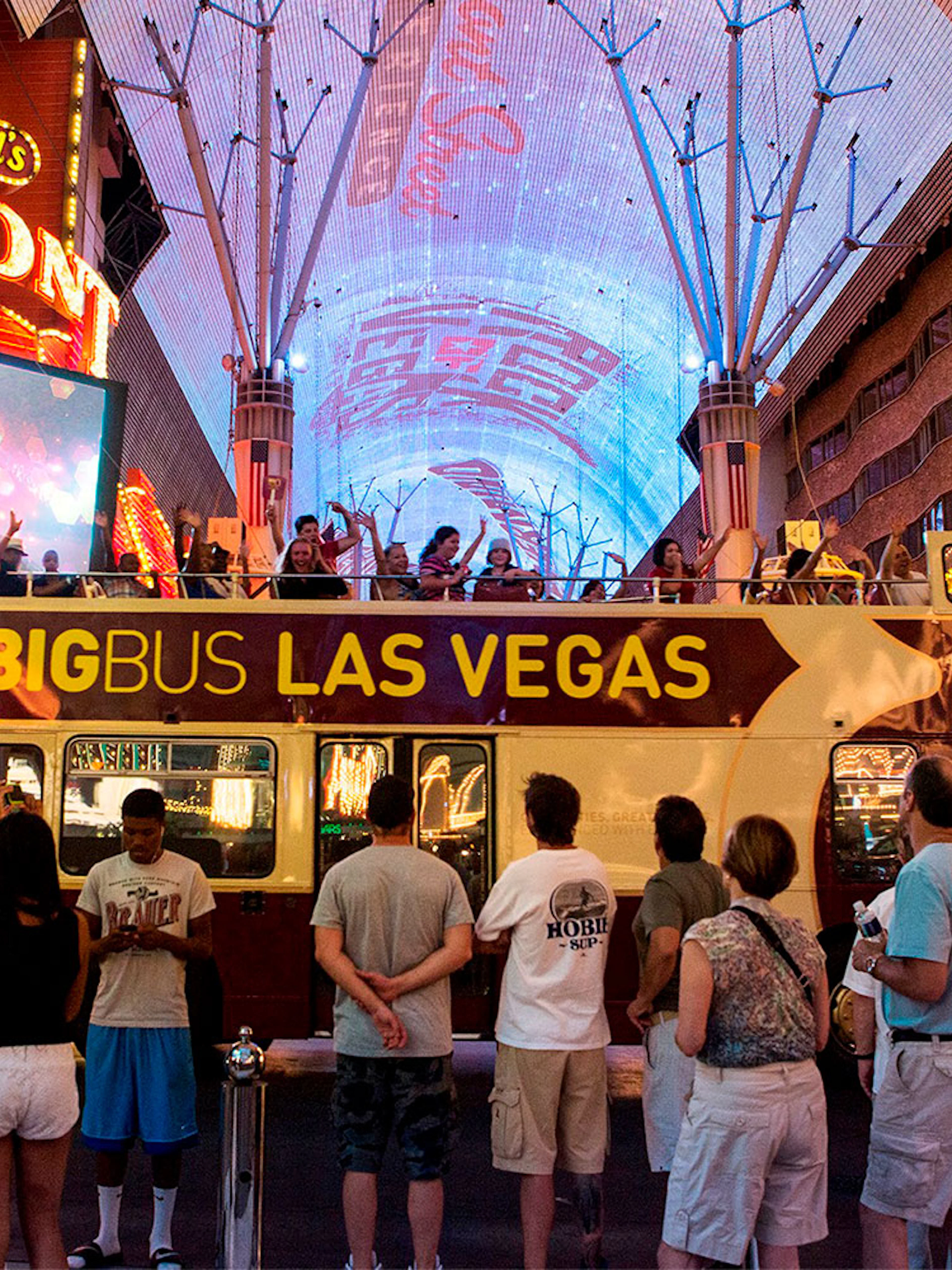 Big Bus tour in Las Vegas at night on Fremont Street with illuminated signs.