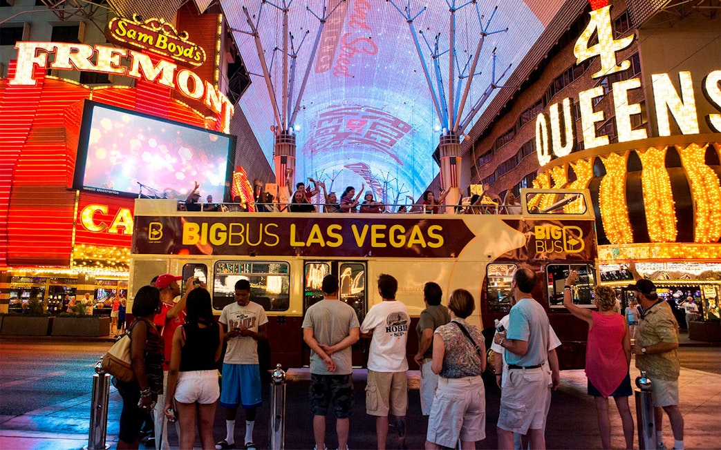 Big Bus tour in Las Vegas at night on Fremont Street with illuminated signs.