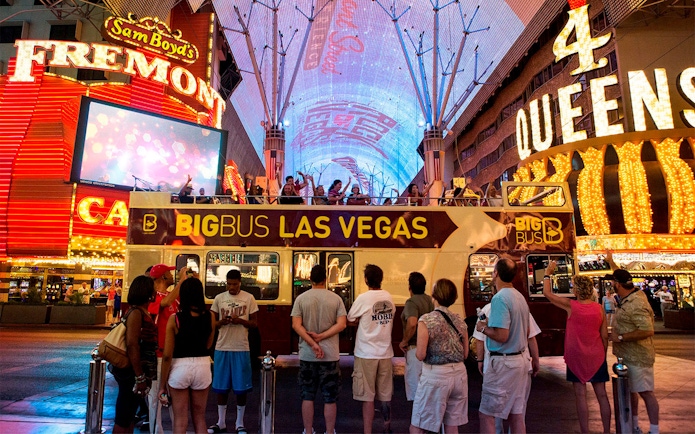 Big Bus tour in Las Vegas at night on Fremont Street with illuminated signs.