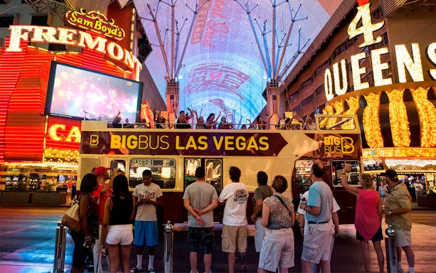 Big Bus tour in Las Vegas at night on Fremont Street with illuminated signs.