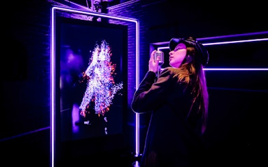Tourist engaging with digital art at Audiovisual Experience in Amaze Amsterdam.