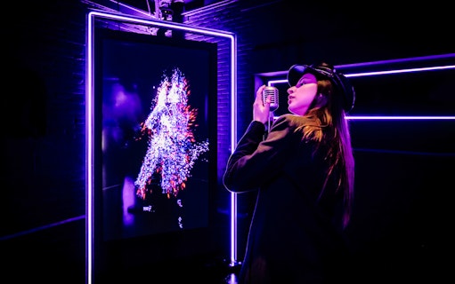 Tourist engaging with digital art at Audiovisual Experience in Amaze Amsterdam.