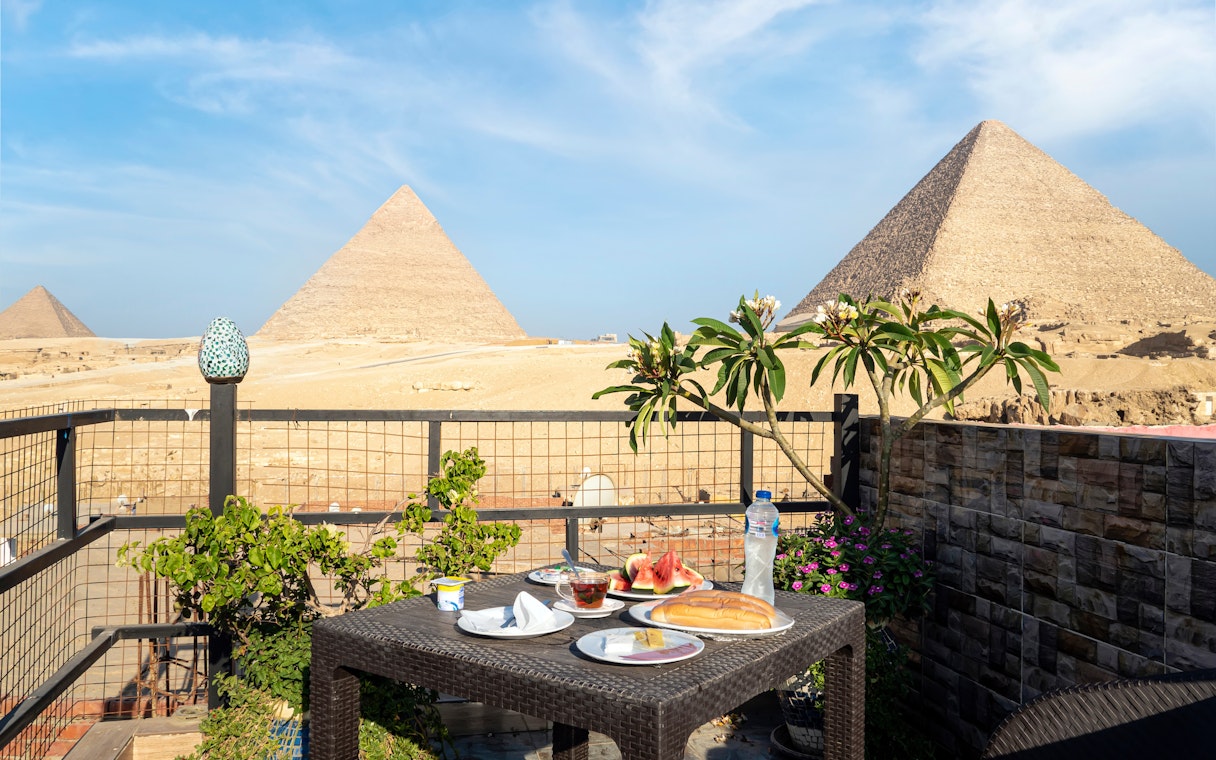 Food on a table with a view of the Giza pyramids in Egypt.