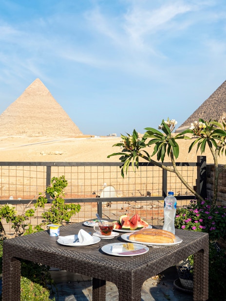 Food on a table with a view of the Giza pyramids in Egypt.