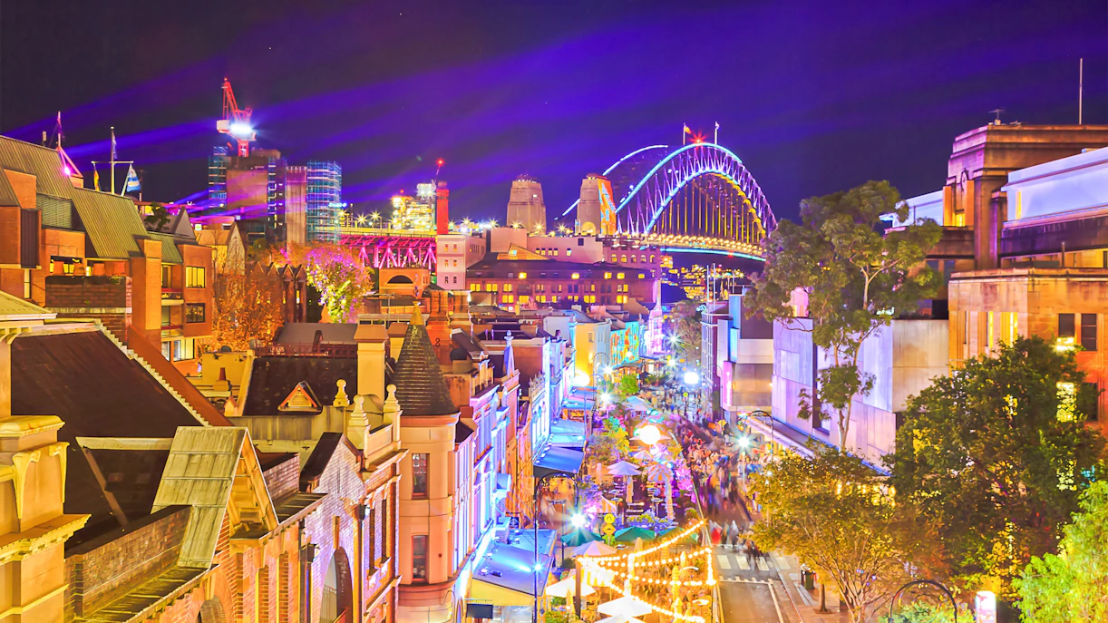 The Rocks Sydney vibrant night scene with Sydney Harbour Bridge in view.