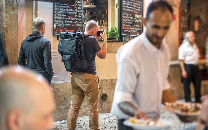 Tourists exploring Alfama's narrow streets with local dining options.