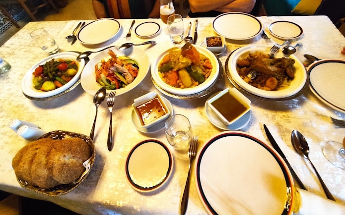Traditional Moroccan dinner table with couscous, vegetables, and bread.