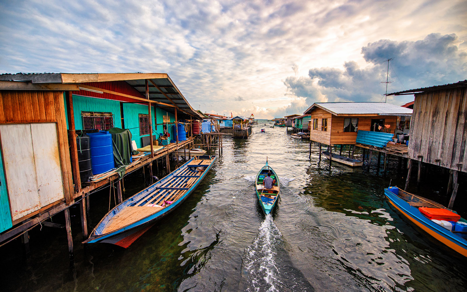Boat navigating between stilt houses in Semporna, Malaysia, near Tawau Airport transfer route.