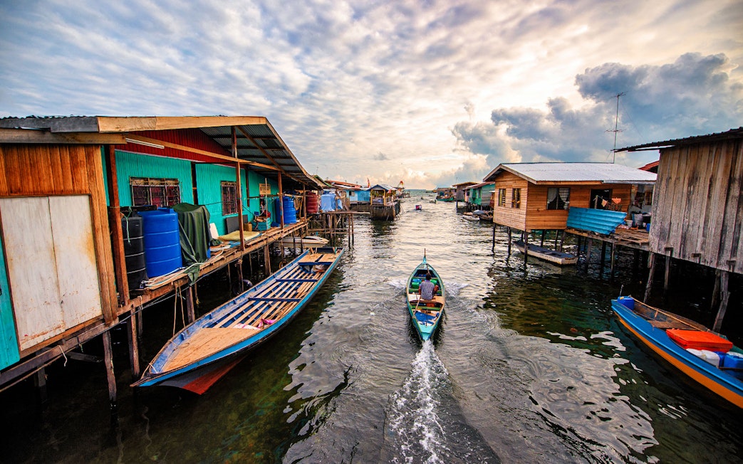 Boat navigating between stilt houses in Semporna, Malaysia, near Tawau Airport transfer route.