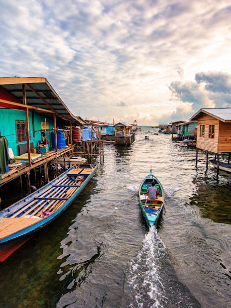 Boat navigating between stilt houses in Semporna, Malaysia, near Tawau Airport transfer route.