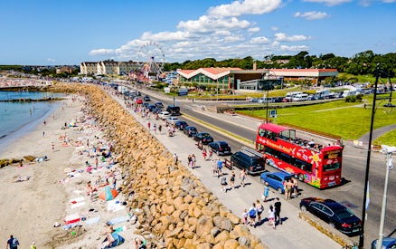 Double-decker bus on Galway Hop-On-Hop-Off Tour passing a busy beach.