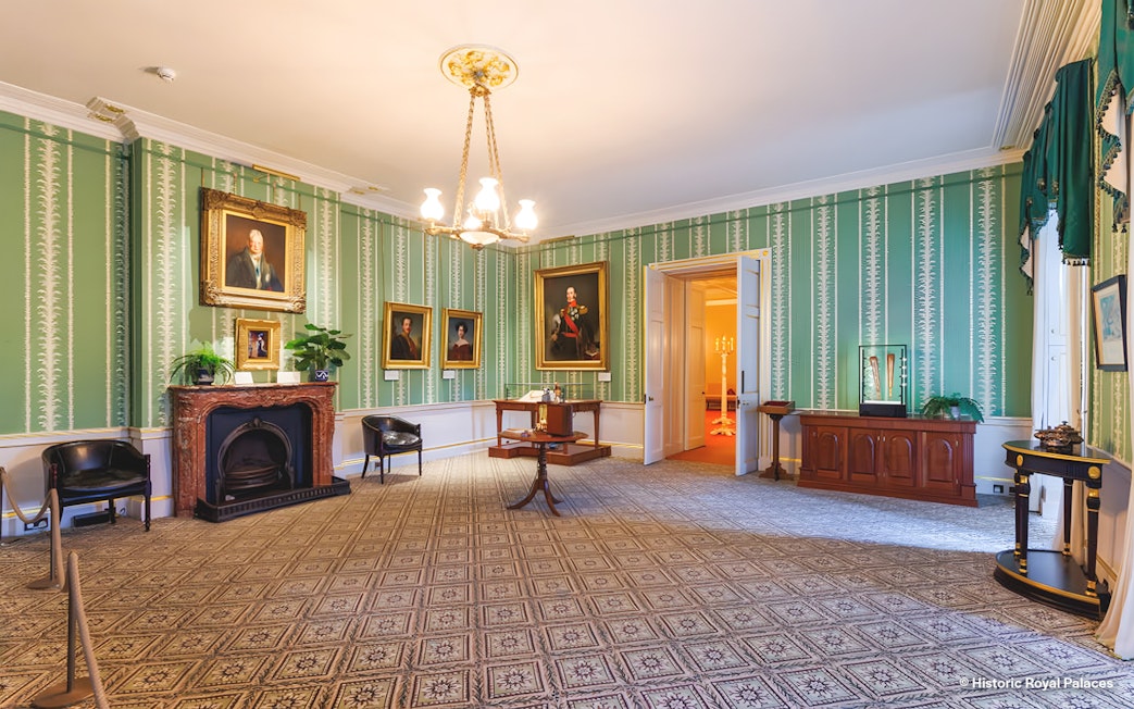 Kensington Palace interior with portraits and ornate fireplace.