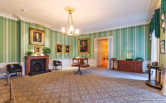 Kensington Palace interior with portraits and ornate fireplace.