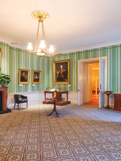 Kensington Palace interior with portraits and ornate fireplace.