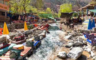 Waterside dining with colorful seating along a stream in Ourika Valley, Morocco.