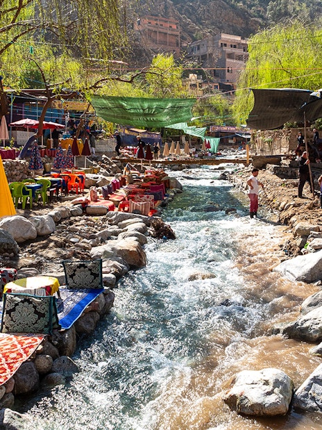 Waterside dining with colorful seating along a stream in Ourika Valley, Morocco.