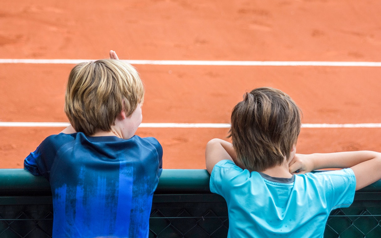 Children observing the clay court at Roland Garros Stadium during a backstage tour.