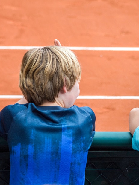 Children observing the clay court at Roland Garros Stadium during a backstage tour.