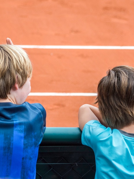Children observing the clay court at Roland Garros Stadium during a backstage tour.