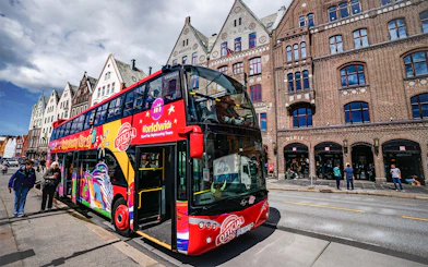 Bergen hop-on hop-off bus in front of historic Bryggen buildings.