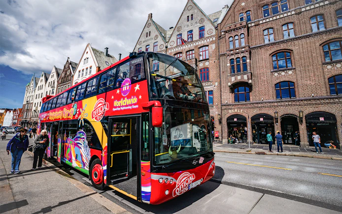 Bergen hop-on hop-off bus in front of historic Bryggen buildings.