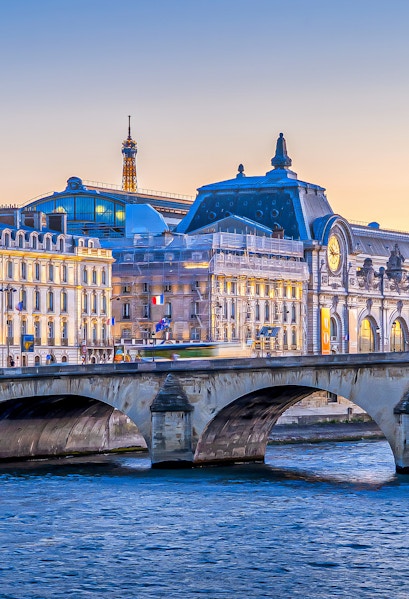 Orsay Museum and Seine River with Eiffel Tower in Paris at sunset.
