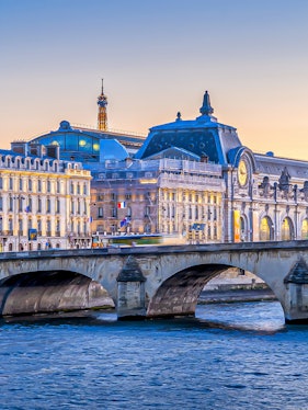 Orsay Museum and Seine River with Eiffel Tower in Paris at sunset.