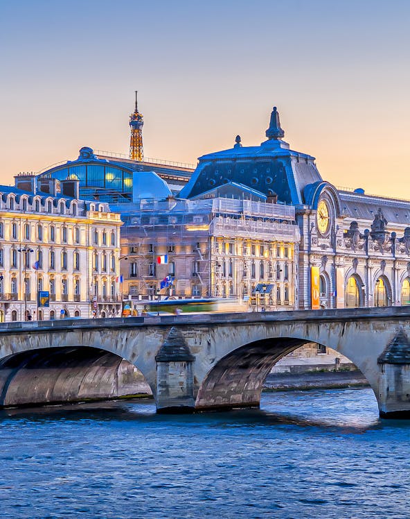 Orsay Museum and Seine River with Eiffel Tower in Paris at sunset.