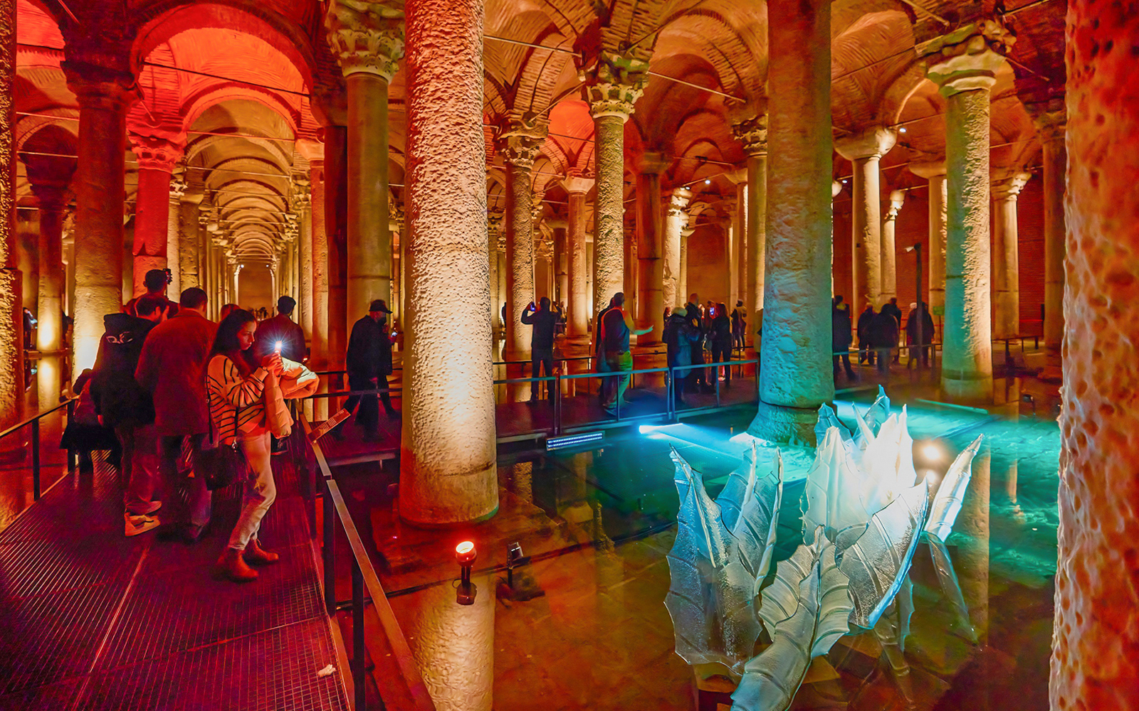 Visitors exploring the illuminated Basilica Cistern in Istanbul.