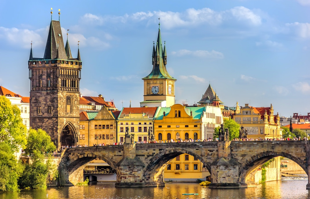 Charles Bridge in Prague with snow-covered rooftops in December.