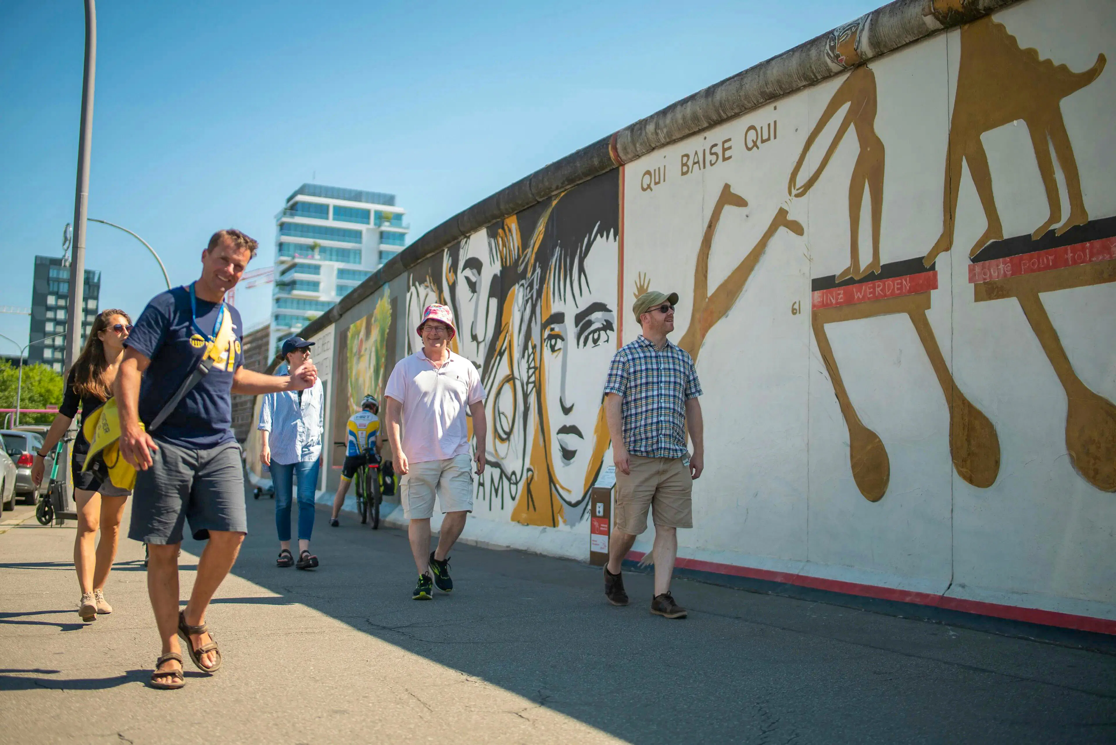 Walking tour group at Berlin Wall's East Side Gallery with murals.