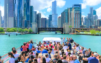 Chicago River cruise with tourists viewing skyline and architecture.