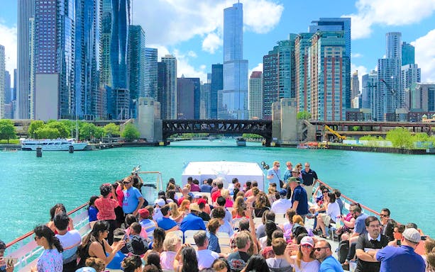 Chicago River cruise with tourists viewing skyline and architecture.