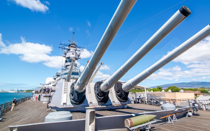 Missouri Battleship Memorial deck with large naval guns under a clear blue sky.