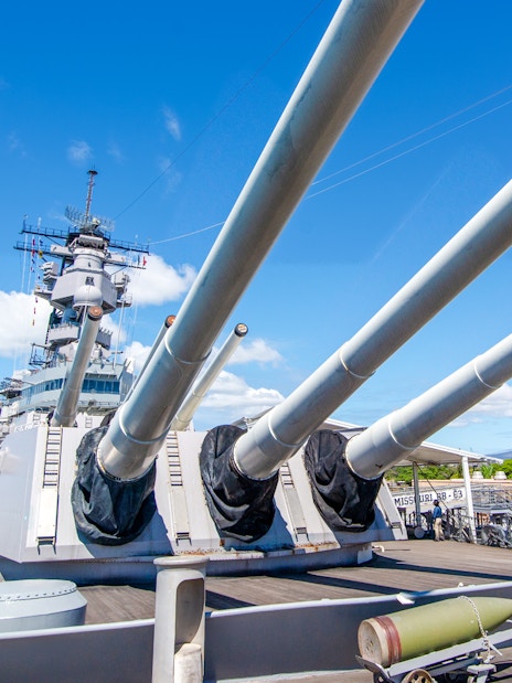 Missouri Battleship Memorial deck with large naval guns under a clear blue sky.