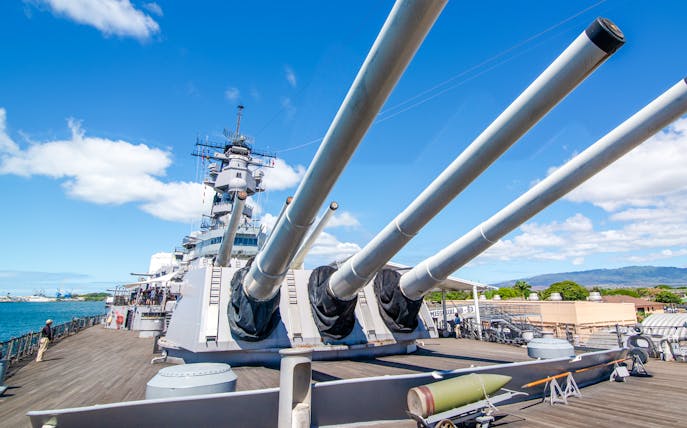 Missouri Battleship Memorial deck with large naval guns under a clear blue sky.