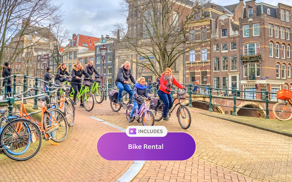 Cyclists riding on an Amsterdam canal bridge with historic buildings in the background.