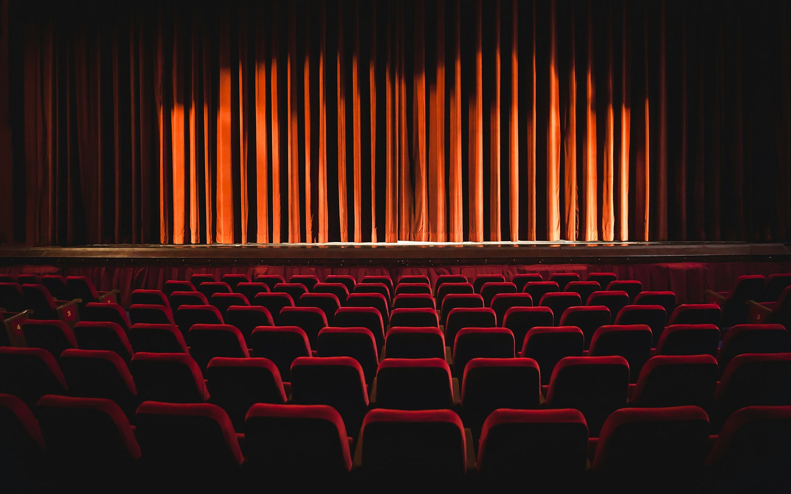 Theatre seats facing a closed stage curtain.