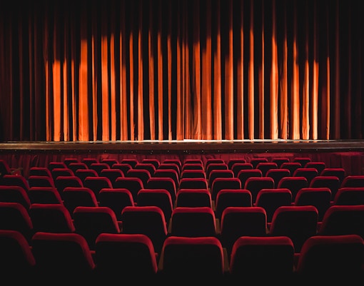 Theatre seats facing a closed stage curtain.
