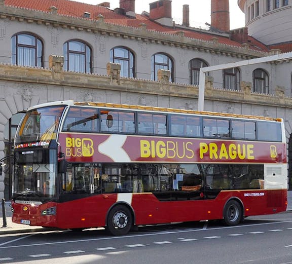 Double-decker Big Bus Prague tour bus parked in front of historic building.