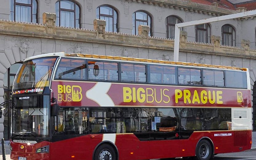 Double-decker Big Bus Prague tour bus parked in front of historic building.