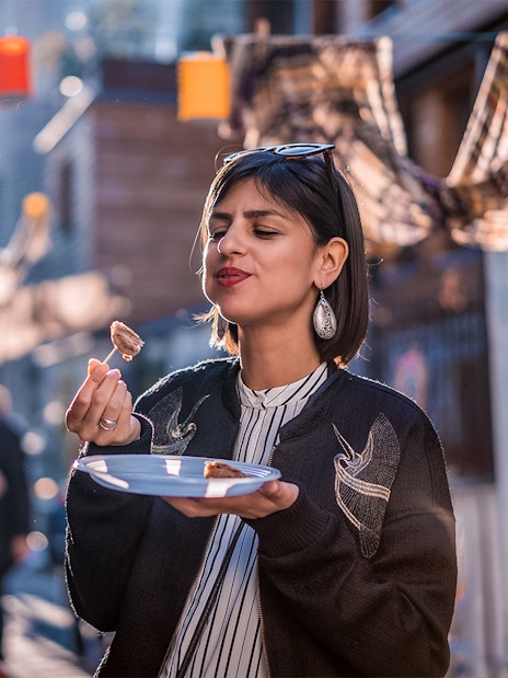 Person enjoying food on a street in Montmartre, Paris during a food tour.