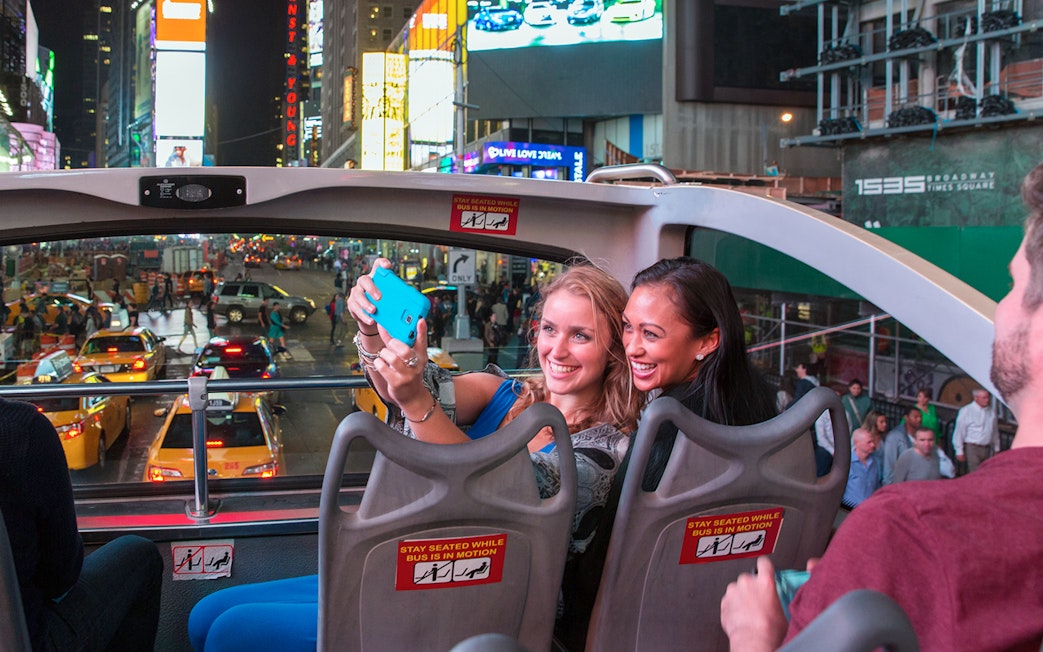 Passengers taking a selfie on a Big Bus night tour in Times Square, New York City.
