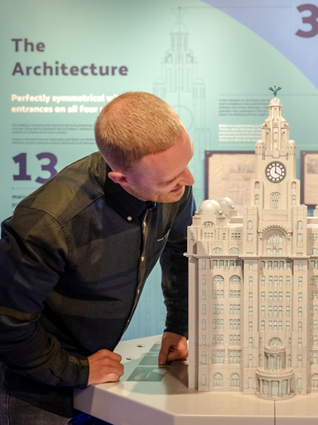 Visitors examining a model of the Royal Liver Building inside the exhibit.