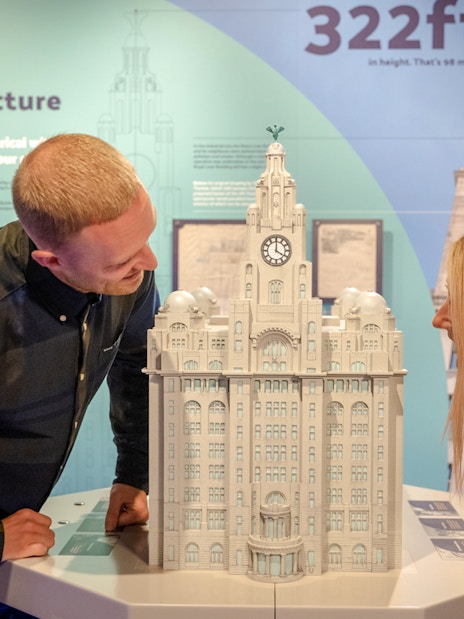Visitors examining a model of the Royal Liver Building inside the exhibit.
