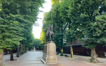 Statue of a historical figure on horseback along a tree-lined path in Boston's Greenway.