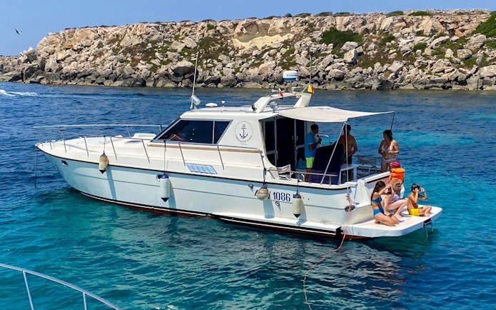 Boat with tourists near rocky coastline on Favignana and Levanzo tour from Marsala.
