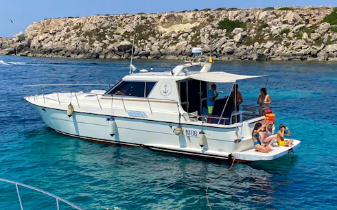 Boat with tourists near rocky coastline on Favignana and Levanzo tour from Marsala.